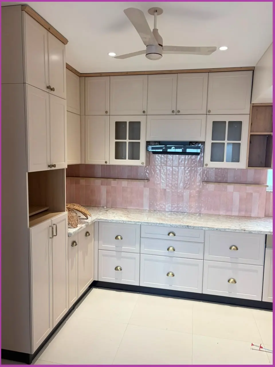 White shaker modular kitchen with glass wall units and pink backsplash, Pune